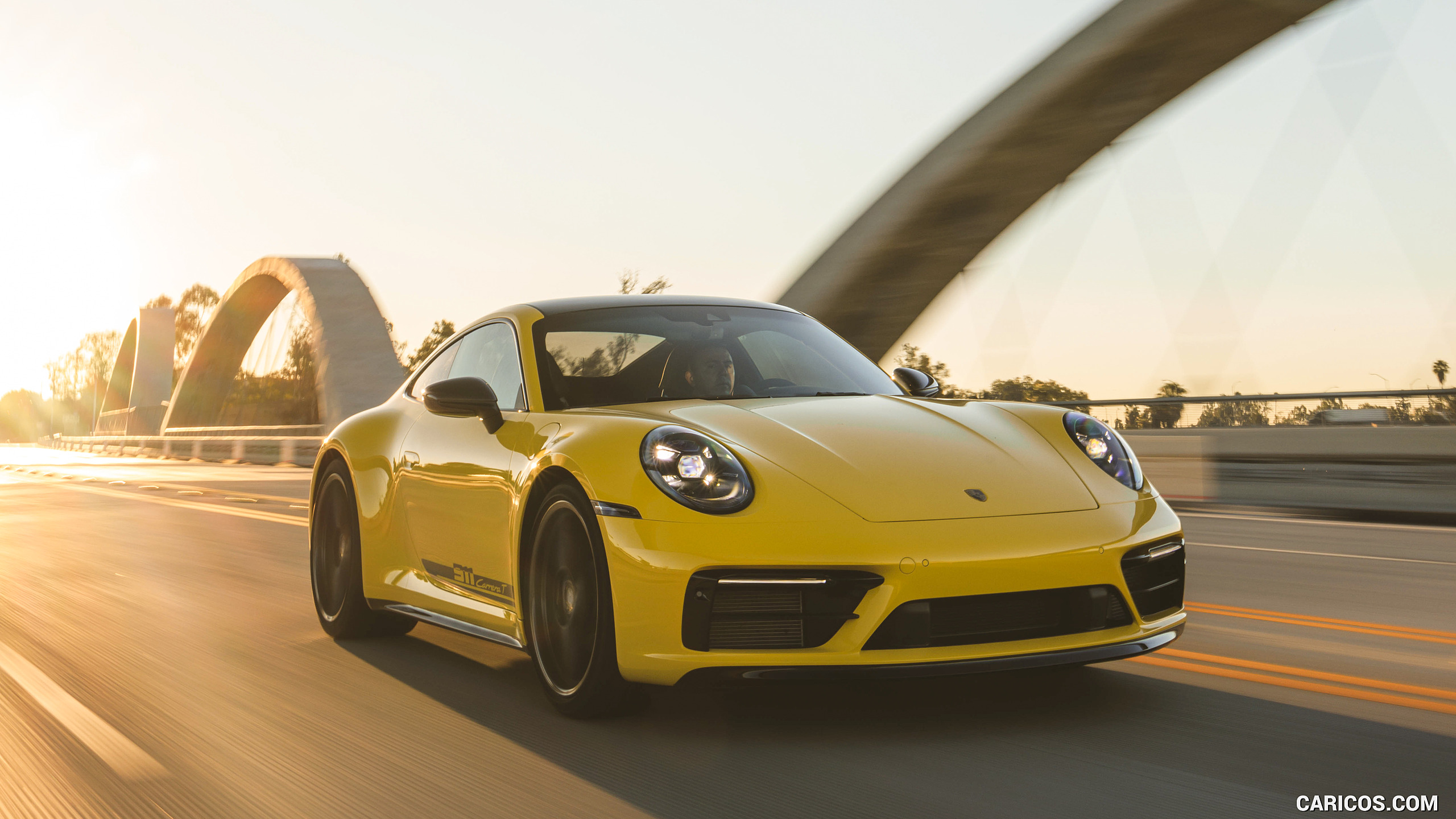 Yellow Porsche 911 driving on an open road