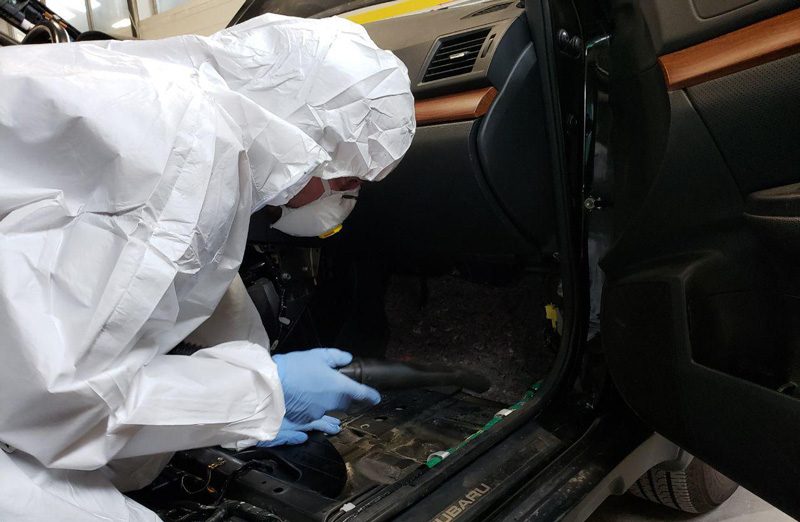 Man in hazard suite detailing a interior of a car with infected with mold