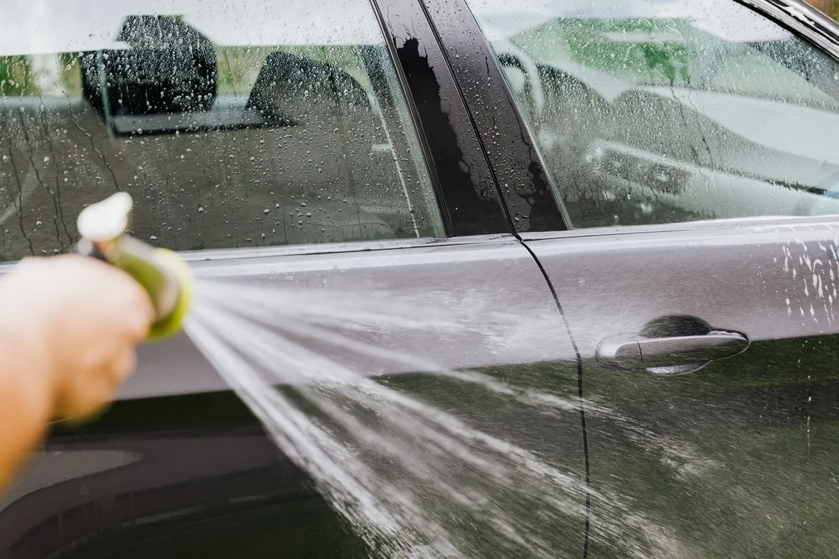 Rinsing a car from the top down — let water float the ash off before anything touches the paint