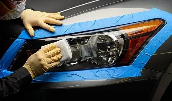 A headlight being restored of a grey car